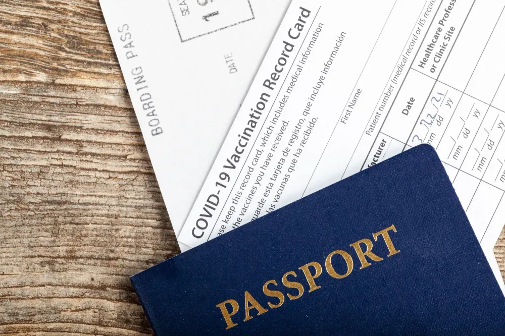Passport, COVID vaccination card, and boarding pass on a wooden background